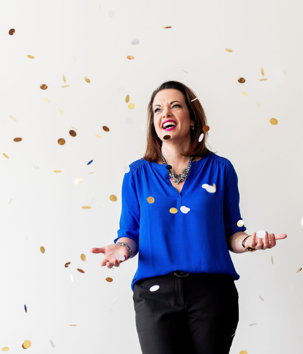 Inspiring woman celebrating success with gold confetti, representing joy and achievement.