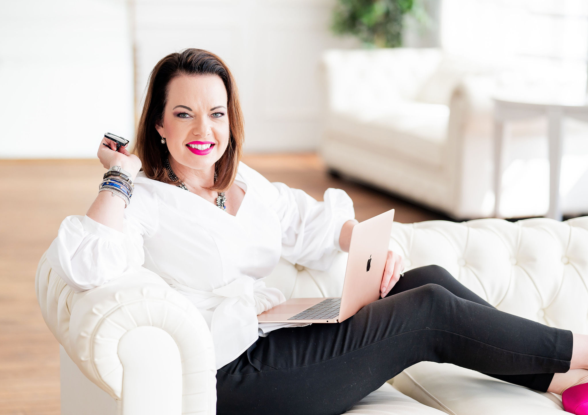 20230922-DSC_6686 Empowered woman sitting on a cream-colored sofa with a laptop, smiling confidently, representing personal growth and resilience for Marie Monville's mental health and motivational content.