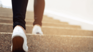 Walking up stairs, symbolizing stepping forward in life or overcoming challenges, with clear focus on shoes and staircase for motivational or inspirational themes.