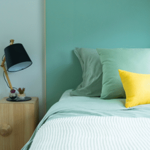 Serene bedroom with green and yellow pillows, modern black bedside lamp, cozy bedding, and minimalist decor, creating a calming space for relaxation and peaceful sleep.