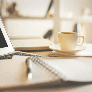 Laptop and coffee cup on a cozy workspace for personal growth and inspiration with Marie Monville.