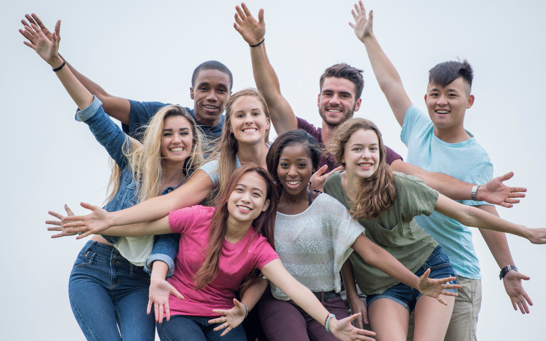 Happy diverse group of young adults celebrating and smiling together, showing joy and friendship, outdoors against a bright sky background, emphasizing community and positivity for SEO.