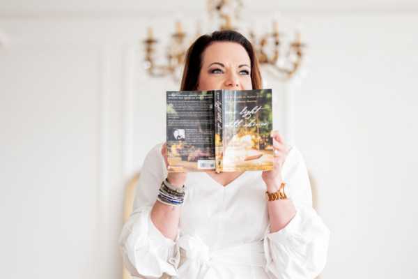 Healing author Marie Monville reading her inspirational book, promoting faith and resilience, in a bright, elegant home setting.